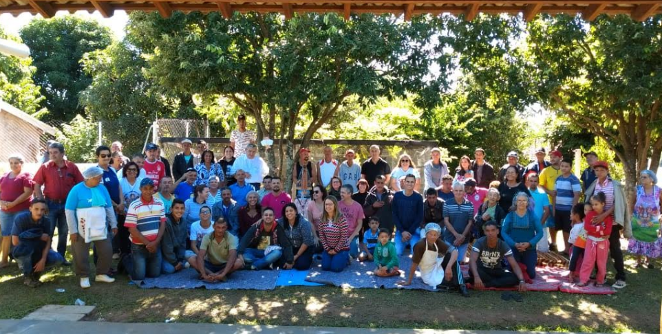 Grande grupo de voluntários e pessoas assistidas reunido ao ar livre