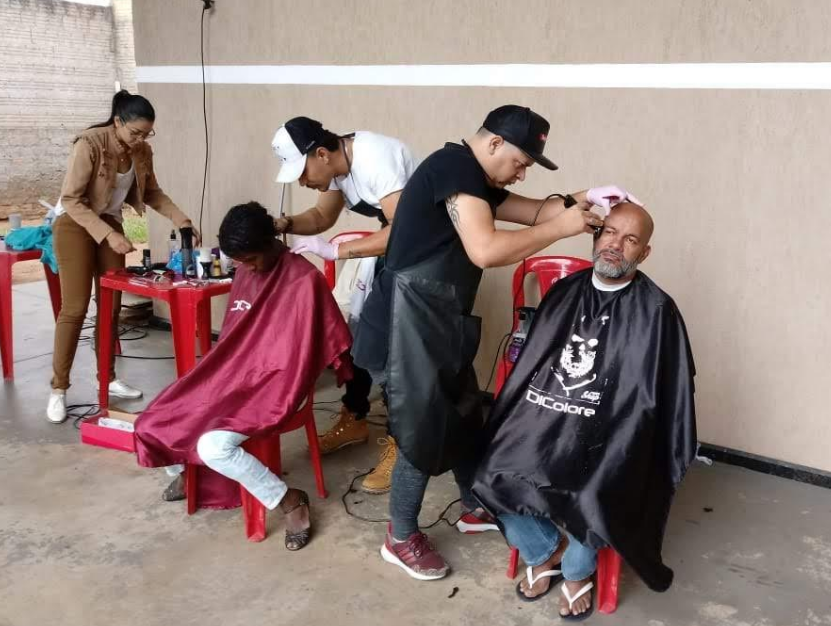 Voluntários realizando cortes de cabelo em pessoas assistidas