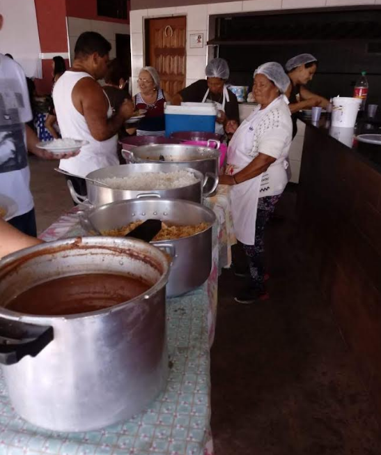 Voluntários preparando refeições em grandes panelas